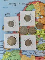 Overview of eight assorted world coins on map background
