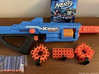 Blaster laid flat with storage units, sealed dart pack and loose darts