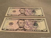 Front of both $5 bills showing serial numbers and condition