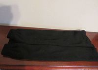 Two folded black skirts on surface