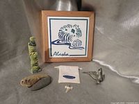 Group shot showing all six items including framed tile, pewter seal, totem pole, pouch, tooth and stone seal