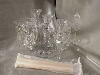 Lead crystal candelabra with dangling prisms, four bud vases, pack of candles