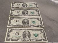 Fronts of four $2 bills showing serial numbers and obverse design