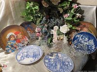 Overview showing collector plates, crystal pieces, cross plaque, floral arrangement, bead bag