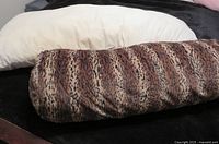 White linen body pillow and animal-print body pillow side by side on dark surface