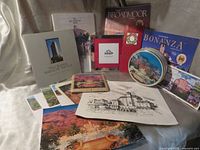 Group shot showing all Broadmoor publications, tin, tile, frame, postcards and print