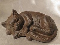Front view of brown cast iron sleeping cat door stop