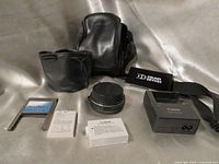 Group shot of all accessories including extension tube, cases, strap, charger, batteries and adapter