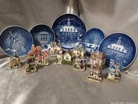 Five “Christmas in America” plates with nine miniature houses arranged below