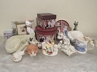 Group shot of all cat figurines, mug, boxes, plate, cow creamer