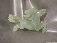 profile view of carved green stone galloping horse statue