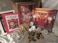 Lot overview showing book, calendars, wall clock, knobs, hooks, bulbs, marbles
