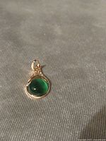 Front view of teardrop pendant showing green stone and gold plated filigree setting