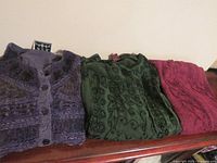 Three folded garments showing colors and embroidery