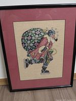 Full view of framed cross-stitch under glass