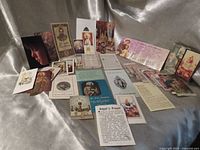 Wide shot of entire assortment of holy cards and pamphlets spread out on fabric backdrop