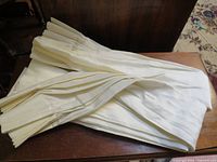 Folded ivory pinch-pleat drapes on table