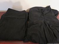 Both black garments folded on surface