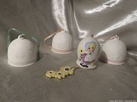 Front view of three matte white Lladro bells and painted sunflower bell