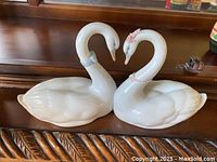 Pair of Lladro swans on wood surface necks forming heart