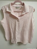 Front view of pink sleeveless polo top on hanger