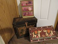 Three wooden pieces grouped: painted cat drawer chest on palm-tree trunk with elephant chest in front