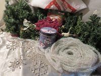 Group shot of all holiday items including potted trees, garland, tins, swag, faux snow