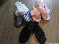 Group shot of three pairs of slippers: pink cross-band, white faux fur, black Dearfoams
