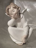 Front view of Lladró Dreaming Angel figurine seated pose