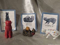 Three Franklin Mint cat figurines with corresponding booklets displayed