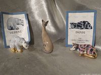 Front view of three cat figurines with two information cards