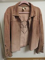 Front view of pink suede jacket showing collar, button front and floral cutouts