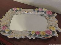 Front view showing ornate floral porcelain frame and mirror glass