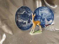 Group shot: standing fawn, sitting iridescent fawn, two Kaiser blue plates