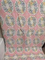 Full view of vintage pink patchwork quilt hung to show overall pattern