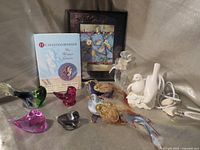 Group shot of all items including lamp, perfume bottle, five glass birds, two clip-on birds, book, framed print