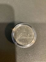 Coin in plastic capsule, reverse side visible with Voyageur design and date 1969