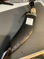 Full view of kukri in black leather sheath