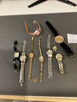 Group shot of all ten vintage wristwatches arranged on surface