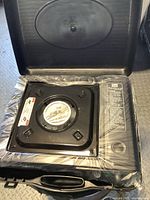 Stove inside open carrying case, still in factory plastic