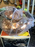 Copper tea kettle sealed in plastic atop its retail box
