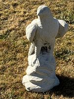 Front angled view of concrete bird statue on grass