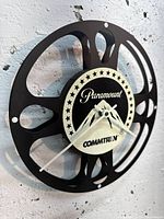 Front view of film reel wall clock showing Paramount Commtron graphics and hands
