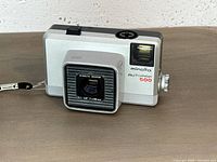 Front view of Minolta Autopak 500 camera showing lens, flash socket, branding