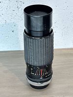 Lens standing upright showing full exterior and built-in hood