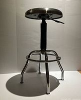 Full view of metal adjustable stool showing seat, legs and footrest