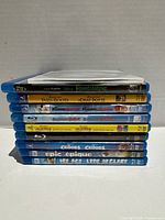 Side view of 10 stacked Blu-ray cases showing visible spine titles and clear slim case on top