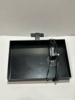 Top view of black clamp tray showing mounting clamp, integrated round wireless charging pad, and attached USB cable