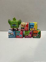 Front view of four sealed Obo papercraft kit boxes with an assembled sample figure displayed
