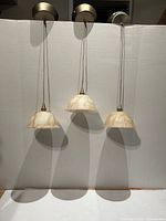 Front view of the three matching pendant lights showing canopies, cords and glass shades